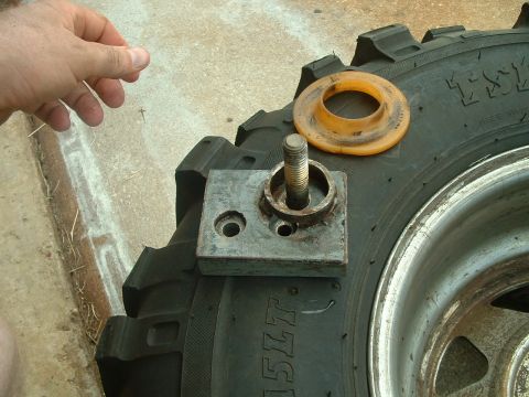 1995 Ford Bronco - A person's hand is visible near a tire with a metal bracket and bolt assembly, along with an orange spacer.
