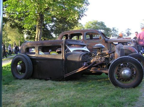 1978 Ford Bronco - A heavily modified rat rod with its engine exposed is parked next to another vintage vehicle.