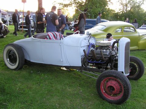 1978 Ford Bronco - A custom hot rod roadster is displayed outdoors with other vehicles and people present.