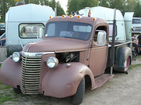 1978 Ford Bronco - A vintage pickup truck, possibly a Chevrolet, is parked next to a camper trailer with a beer bottle on its roof.