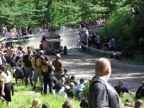 1978 Ford Bronco - A vintage hot rod car kicks up dust as it races on a dirt track, observed by a crowd of spectators.