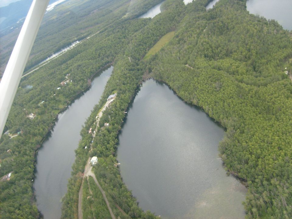 Aerial view of winding lakes and dense green forests, with a few scattered buildings visible along the shorelines
