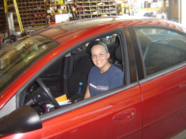 Red car interior with woman driver. Supermotors.net logo visible