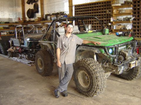 1992 Ford Bronco - A man poses with a heavily modified green off-road vehicle in a workshop.