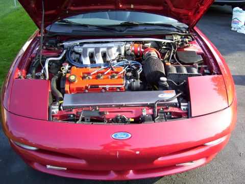 1995 Ford Probe - The engine bay of a red 1995 Ford Probe, an aftermarket air intake and custom engine covers.