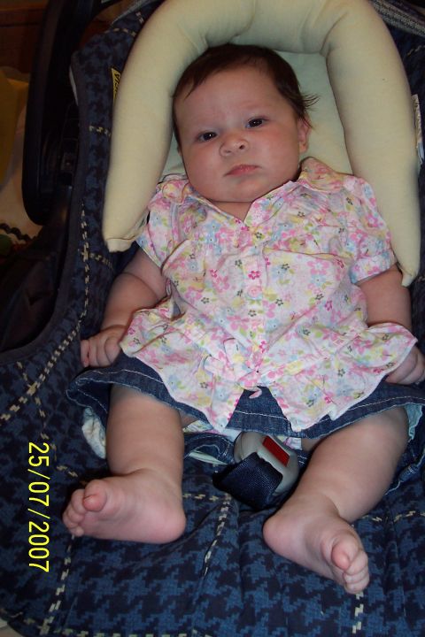2000 Ford Crown Victoria - A baby sits in a car seat, wearing a floral shirt and denim skirt.