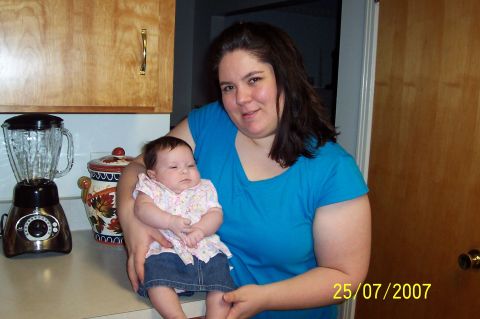 2000 Ford Crown Victoria - A woman holds a baby in a kitchen setting, with a blender and a decorative jar visible on the counter.