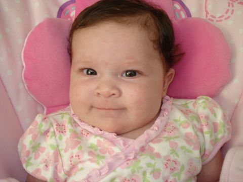 2000 Ford Crown Victoria - A baby girl smiles while wearing a pink floral outfit and resting on a pink pillow.