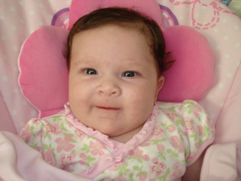 2000 Ford Crown Victoria - A baby girl smiles while resting in a pink cushioned seat.