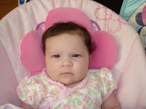 2000 Ford Crown Victoria - A baby with dark hair and a serious expression rests in a pink bouncy seat adorned with flowers.