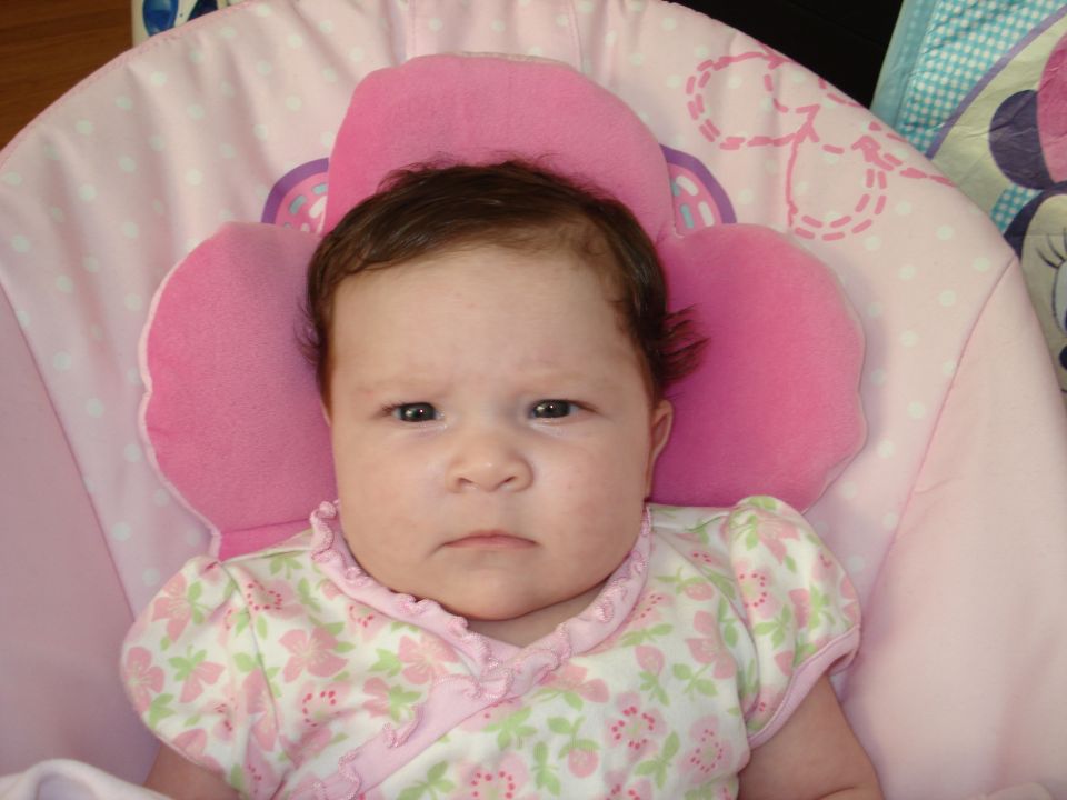 Baby in pink bouncy seat with floral pattern