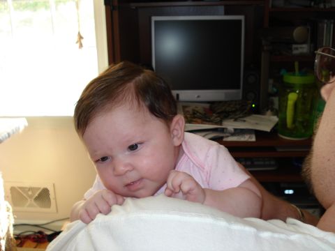 2000 Ford Crown Victoria - A baby is lying on a white blanket, propped up on its arms, with a computer and shelves in the background.