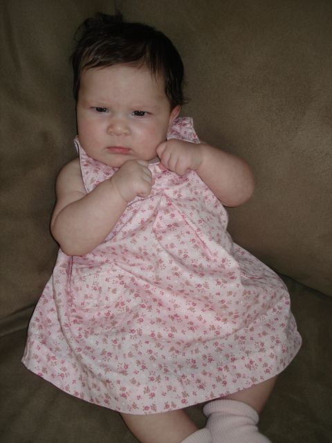 2000 Ford Crown Victoria - A baby with dark hair and a serious expression wears a pink floral dress and pink socks.