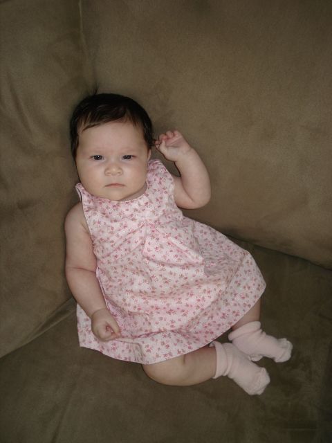 2000 Ford Crown Victoria - A baby girl wearing a pink dress and socks is resting on a couch.