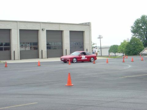 1997 Ford Probe - A red 1997 Ford Probe navigates a course marked by orange cones in front of a building with garage doors.