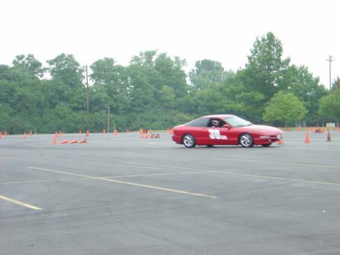 1997 Ford Probe - A red sports car navigates a course marked by orange cones on a paved track.