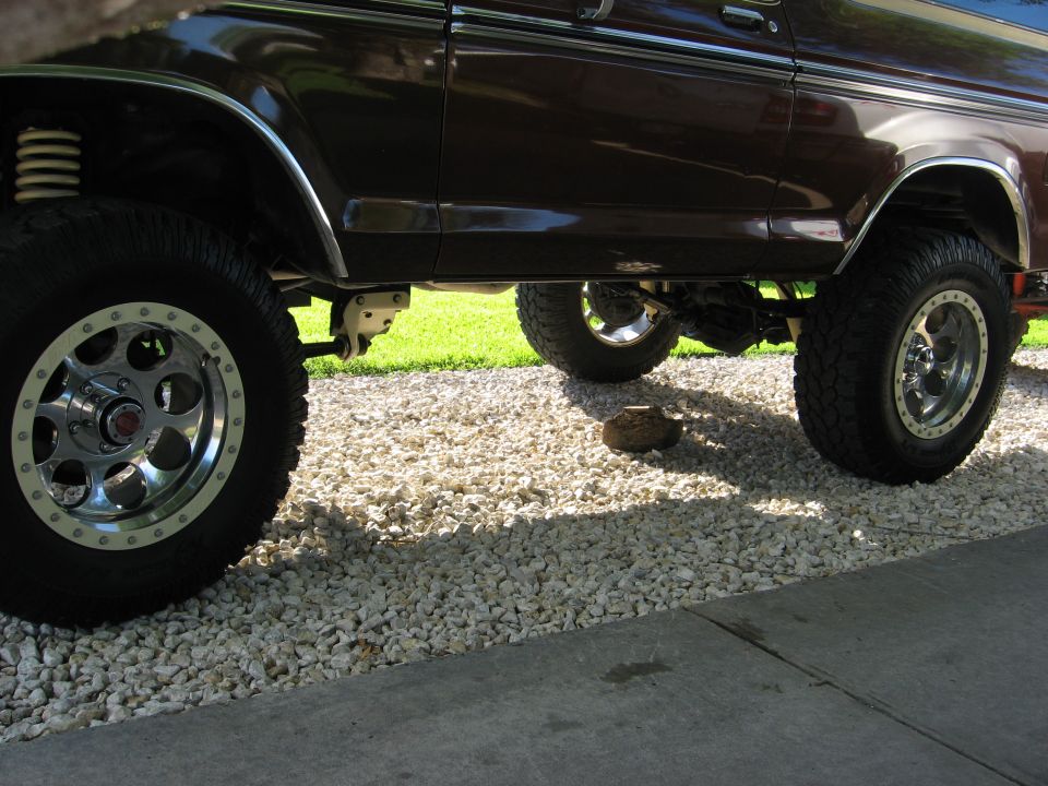 Brown lifted SUV side view with custom wheels and off-road tires