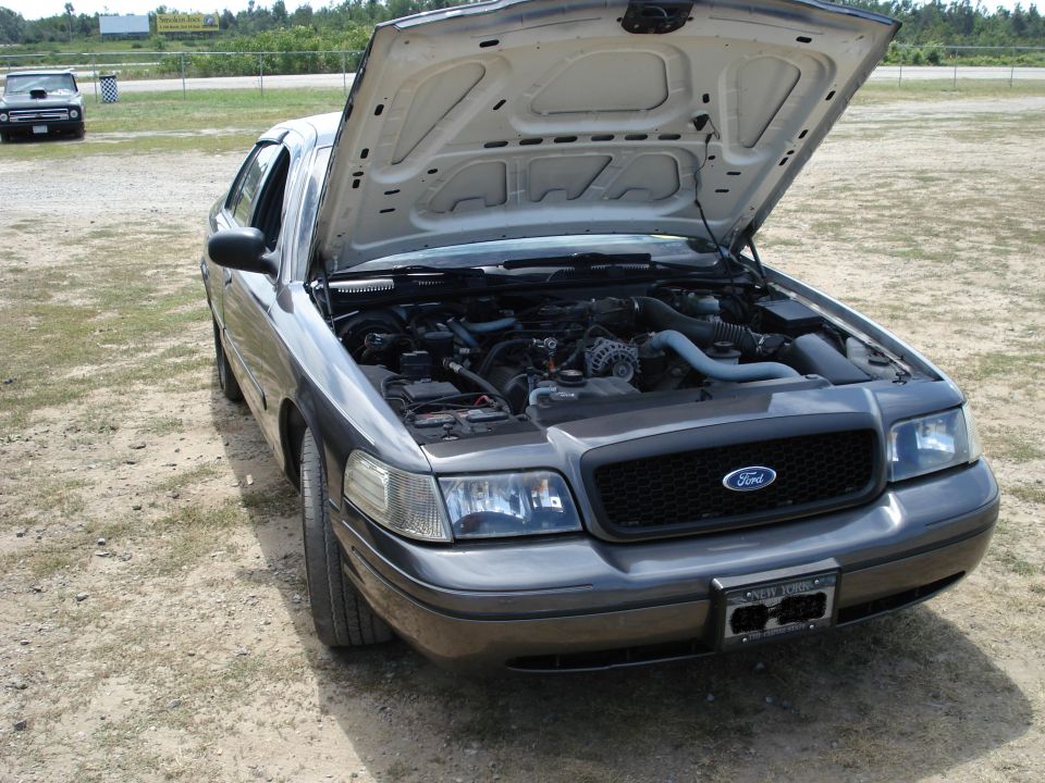 2000 Ford Crown Victoria with hood open, showing engine. Another car is visible in the background