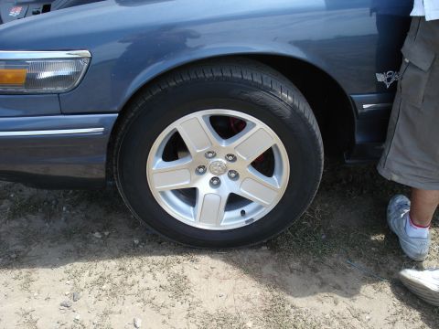 2000 Ford Crown Victoria - A blue sedan is parked outdoors, with a focus on its front wheel and a portion of the fender.