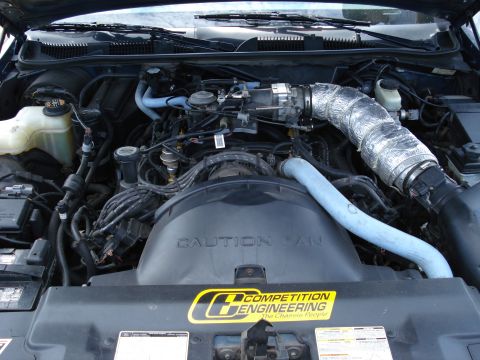 2000 Ford Crown Victoria - The engine bay is visible, with a large fan shroud and a "Competition Engineering" sticker.