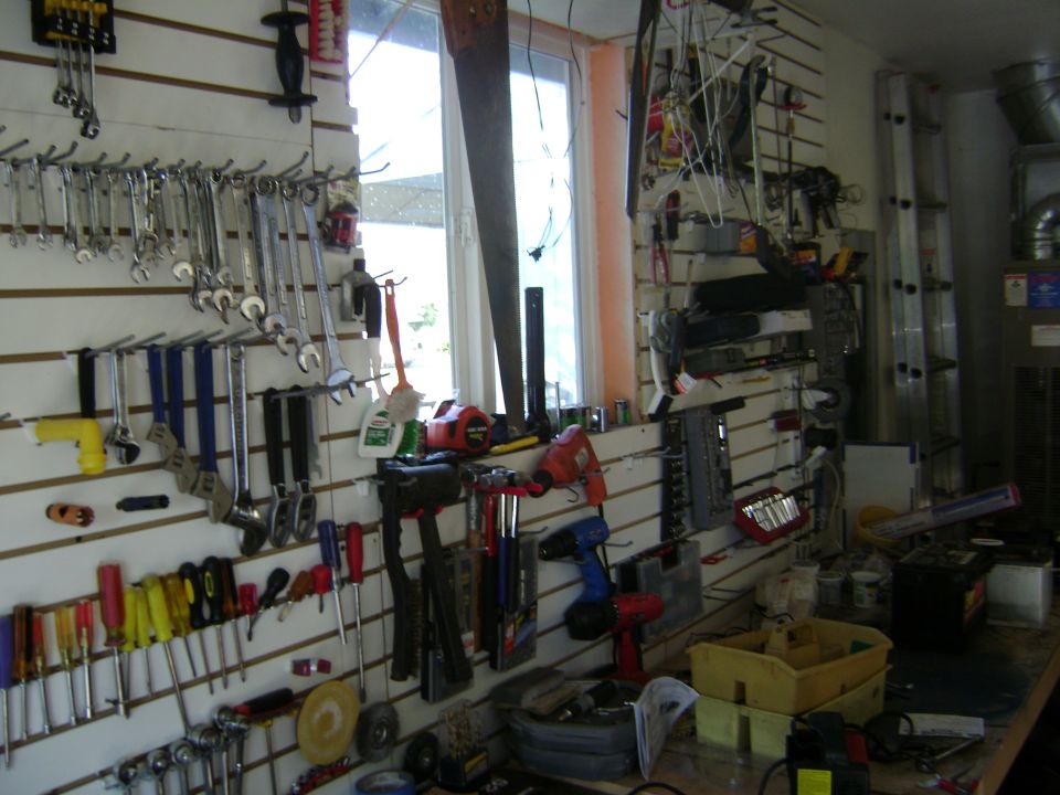Wall of tools including wrenches, screwdrivers, drills, and saws. Window in background