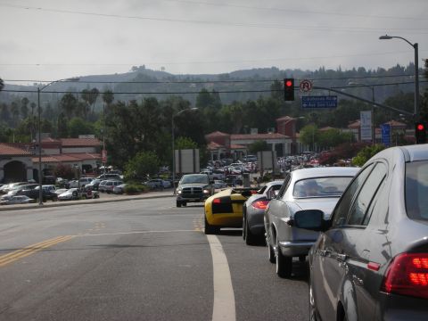 1998 Ford Crown Victoria - A traffic jam on a road with several cars, including a yellow sports car and silver vehicles, under a hazy sky.