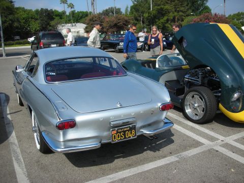 1998 Ford Crown Victoria - Two classic sports cars parked at an outdoor gathering, one a Volvo P1800, the other a green and yellow model.