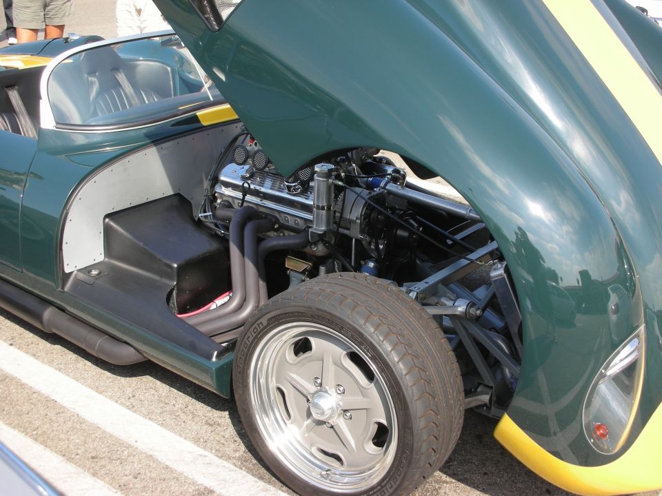 Green race car with yellow stripes, hood open showing engine and front wheel