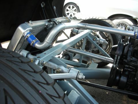 1998 Ford Crown Victoria - Close-up view of a custom suspension system and radiator, with another vehicle partially visible in the background.