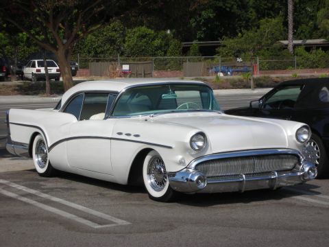 1998 Ford Crown Victoria - A white 1955 Buick Special coupe is parked next to a black convertible.