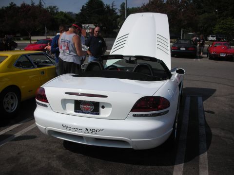 1998 Ford Crown Victoria - A white convertible sports car is parked with its hood open, displaying a "Venom 1000hp Twin Turbo" decal on the rear.