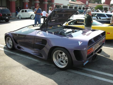 1998 Ford Crown Victoria - A custom purple sports car with its engine exposed is parked at an outdoor event.