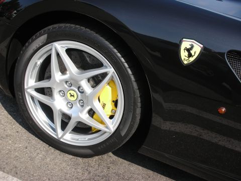 1998 Ford Crown Victoria - Ferrari emblem on the fender of a black car, showing the wheel and yellow brake caliper.