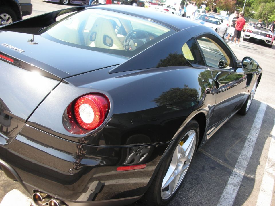 Black Ferrari coupe, rear 3/4 view, showing taillight and alloy wheel