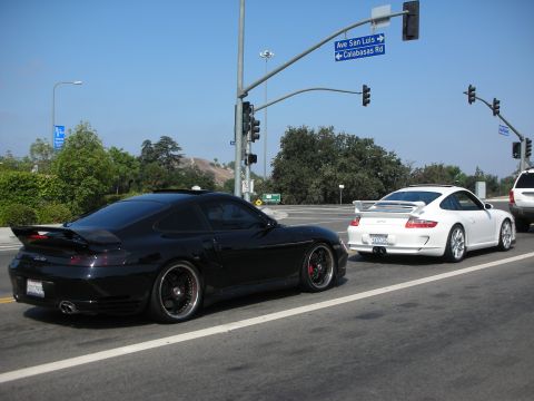 1998 Ford Crown Victoria - Two Porsches, a black 911 and a white 911 GT3, at an intersection with street signs for Ave San Luis and Calabasas Rd.