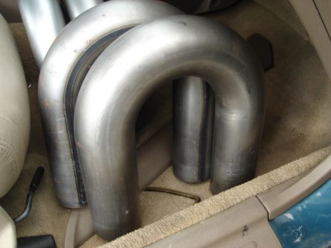 1995 Mazda MX-6 - Exhaust pipes are seen inside a vehicle, resting on the floor and near a seat.