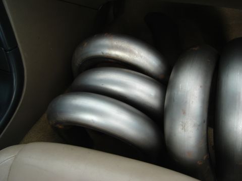 1995 Mazda MX-6 - Several exhaust pipes are visible inside the interior of a vehicle, likely for a turbo project.