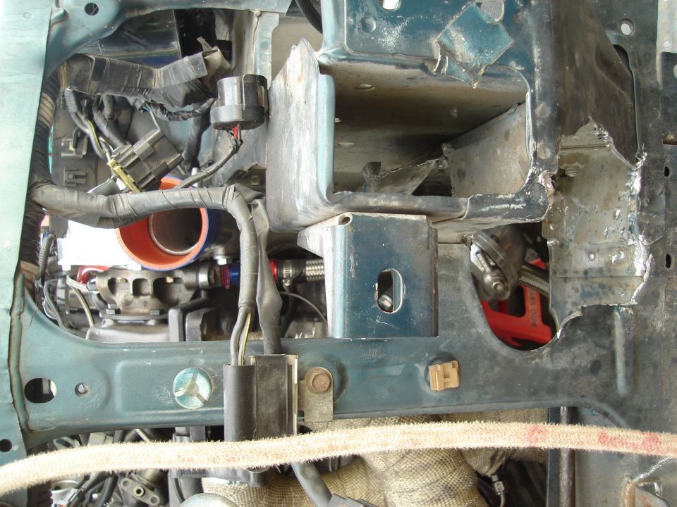 Close-up of a car's engine bay, showing exposed metal, wiring, and turbo piping