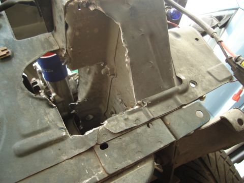 1995 Mazda MX-6 - Close-up of a damaged vehicle engine bay structure, showing metal fatigue and a blue oil filter.