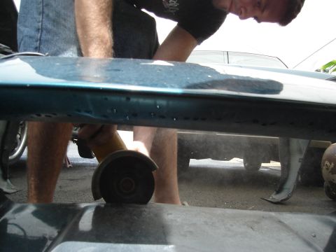 1995 Mazda MX-6 - Angle grinder in use on a vehicle's body panel. Another car is visible in the background.