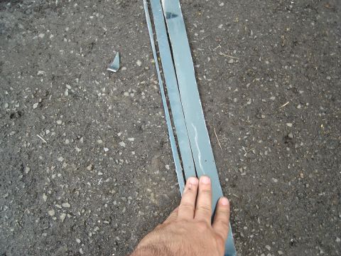 1995 Mazda MX-6 - Metal trim pieces are shown on an asphalt surface, with a hand present.