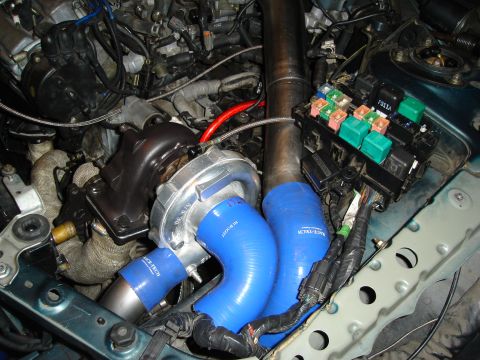 1995 Mazda MX-6 - Close-up of a turbocharger installation with blue hoses and a fuse box.