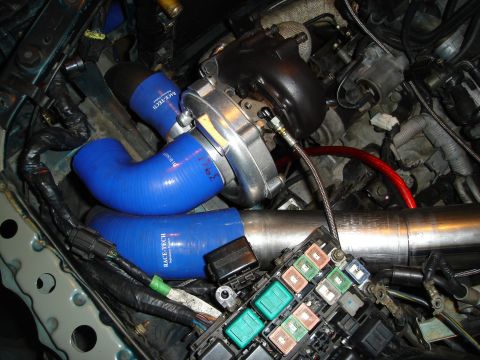 1995 Mazda MX-6 - Custom turbocharger setup with blue silicone hoses and a prominent turbo unit in the engine bay.