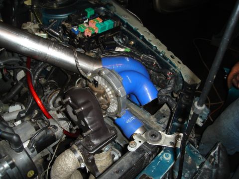 1995 Mazda MX-6 - Custom turbocharger installation in the engine bay of a 1995 Mazda MX-6, showing blue hoses and a fuse box.