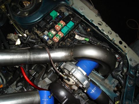 1995 Mazda MX-6 - Close-up view of a modified engine bay, highlighting a turbocharger installation and fuse box.