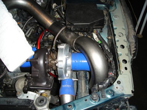 1995 Mazda MX-6 - Custom turbocharger installation in an engine bay, showing intake piping and a fuse box.