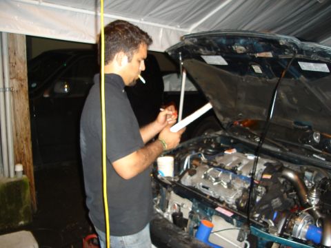 1995 Mazda MX-6 - A person examines notes while standing by a car with its hood open, revealing the engine compartment.