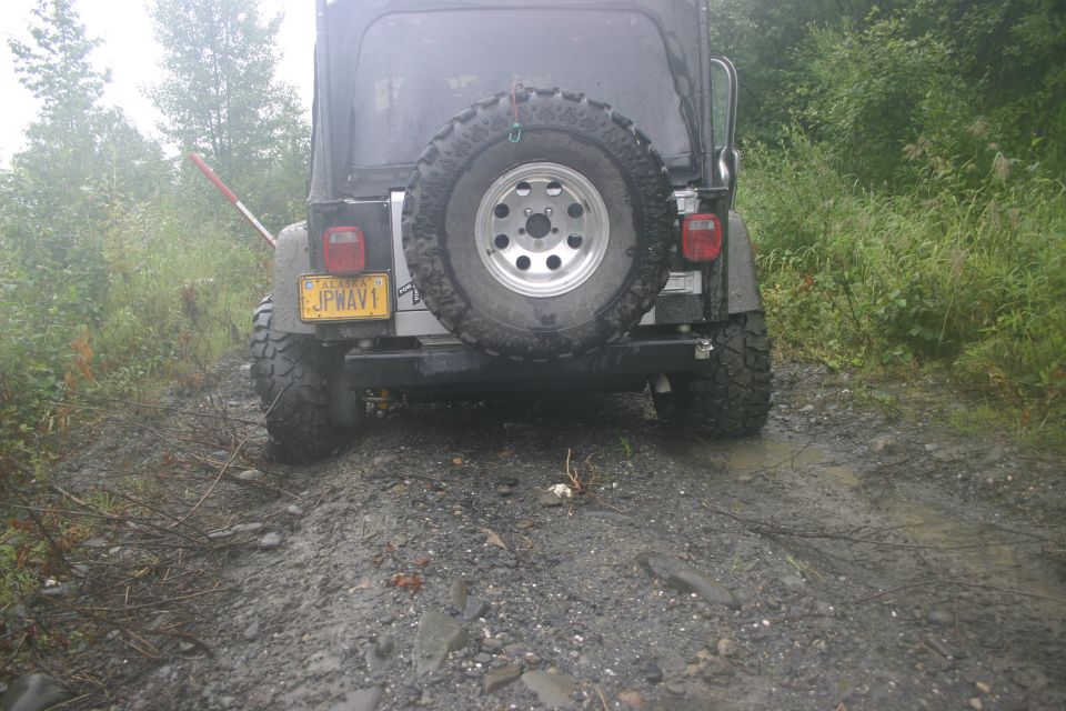 Rear view of a 2003 Jeep TJ on a muddy road