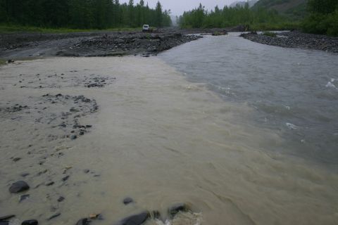 2003 Jeep TJ - A white SUV is parked on a gravel road next to a river where two different colored water currents meet.