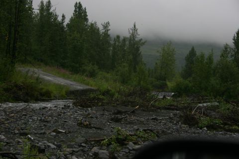 2003 Jeep TJ - A washed-out road crosses a stream bed, surrounded by dense trees and fog.
